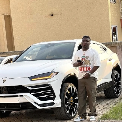 Abu Trica posing with a luxury vehicle