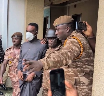 Police inspector being ushered by prison officers from the court